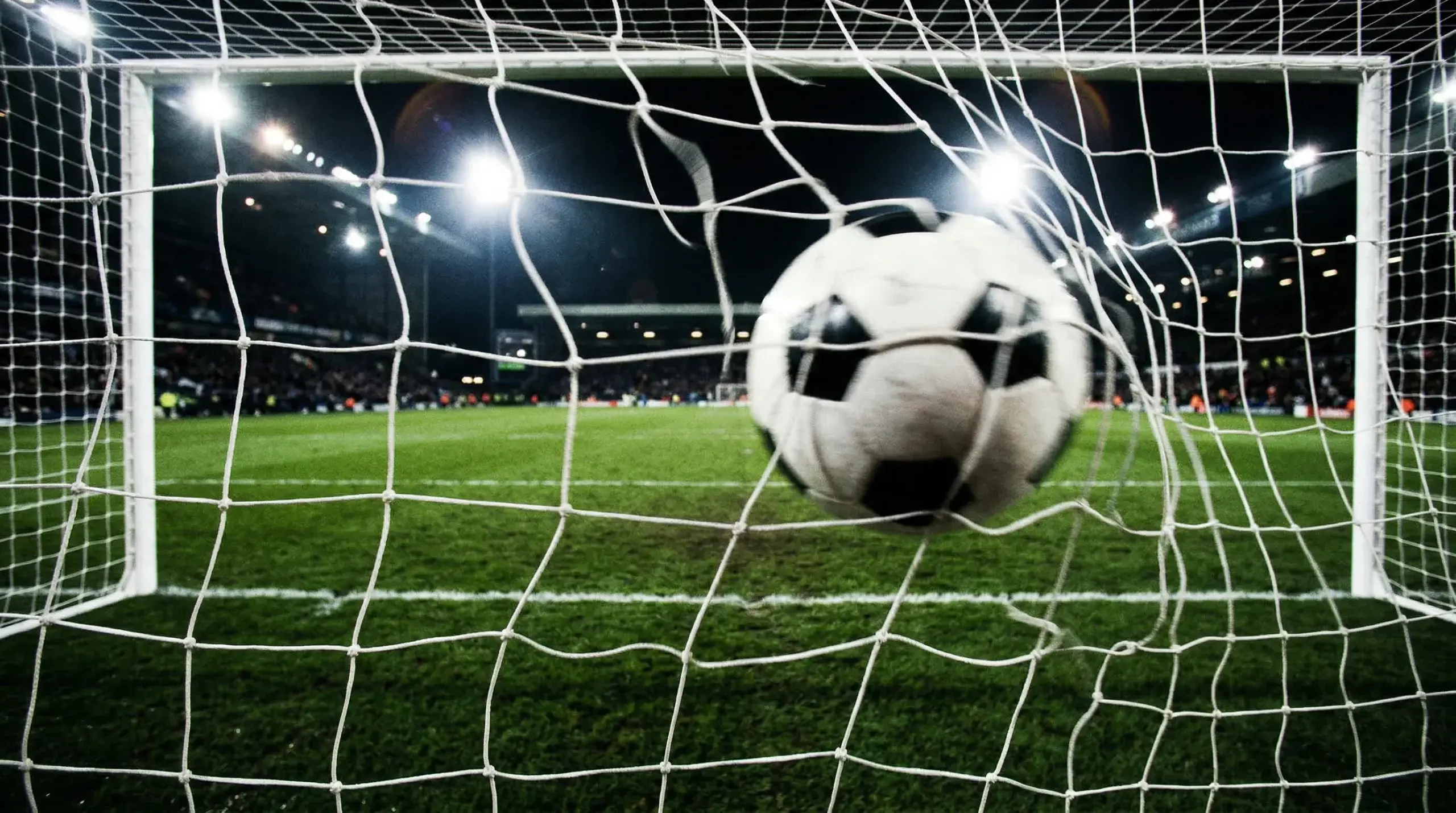 Red de un arco de fútbol profesional vista desde adentro del arco con una pelota entrando al gol